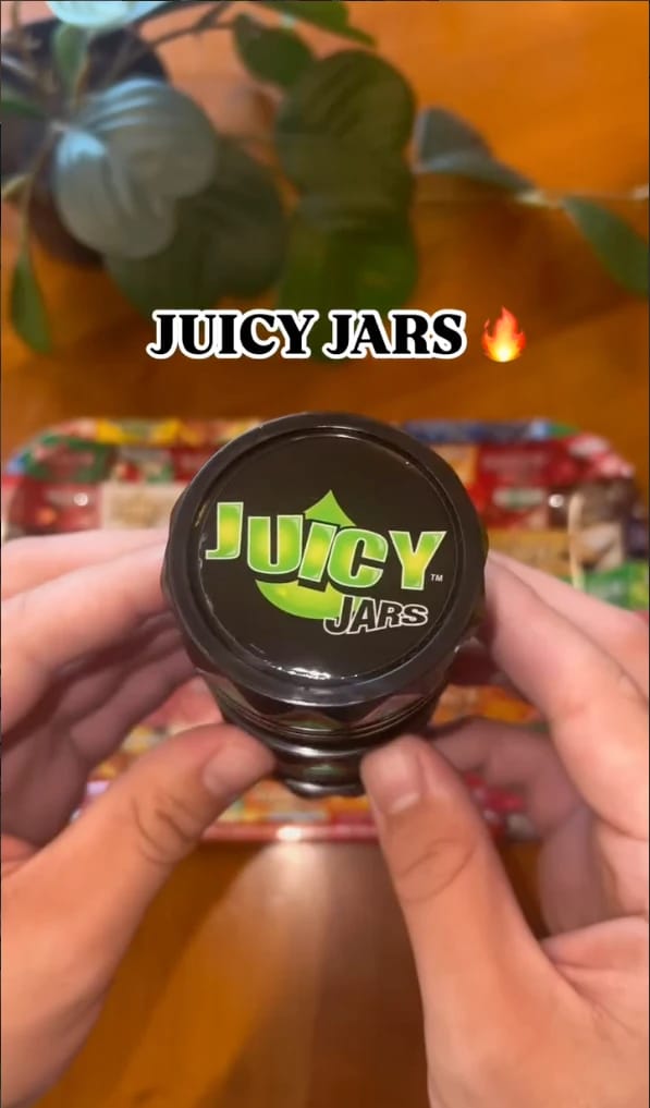 Hands holding a black Juicy Jars storage jar with a green logo